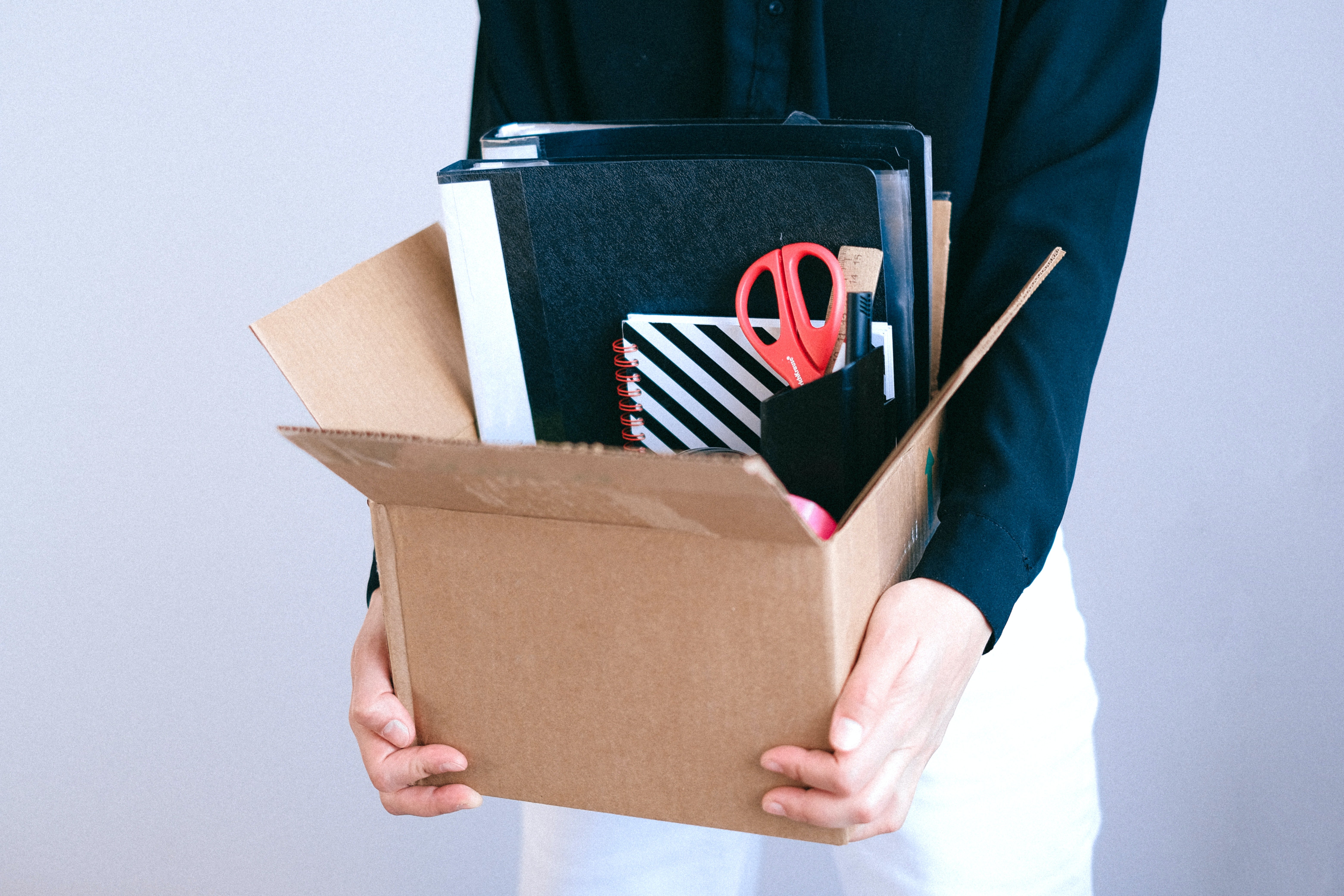 unemployment; woman carrying box with desk items